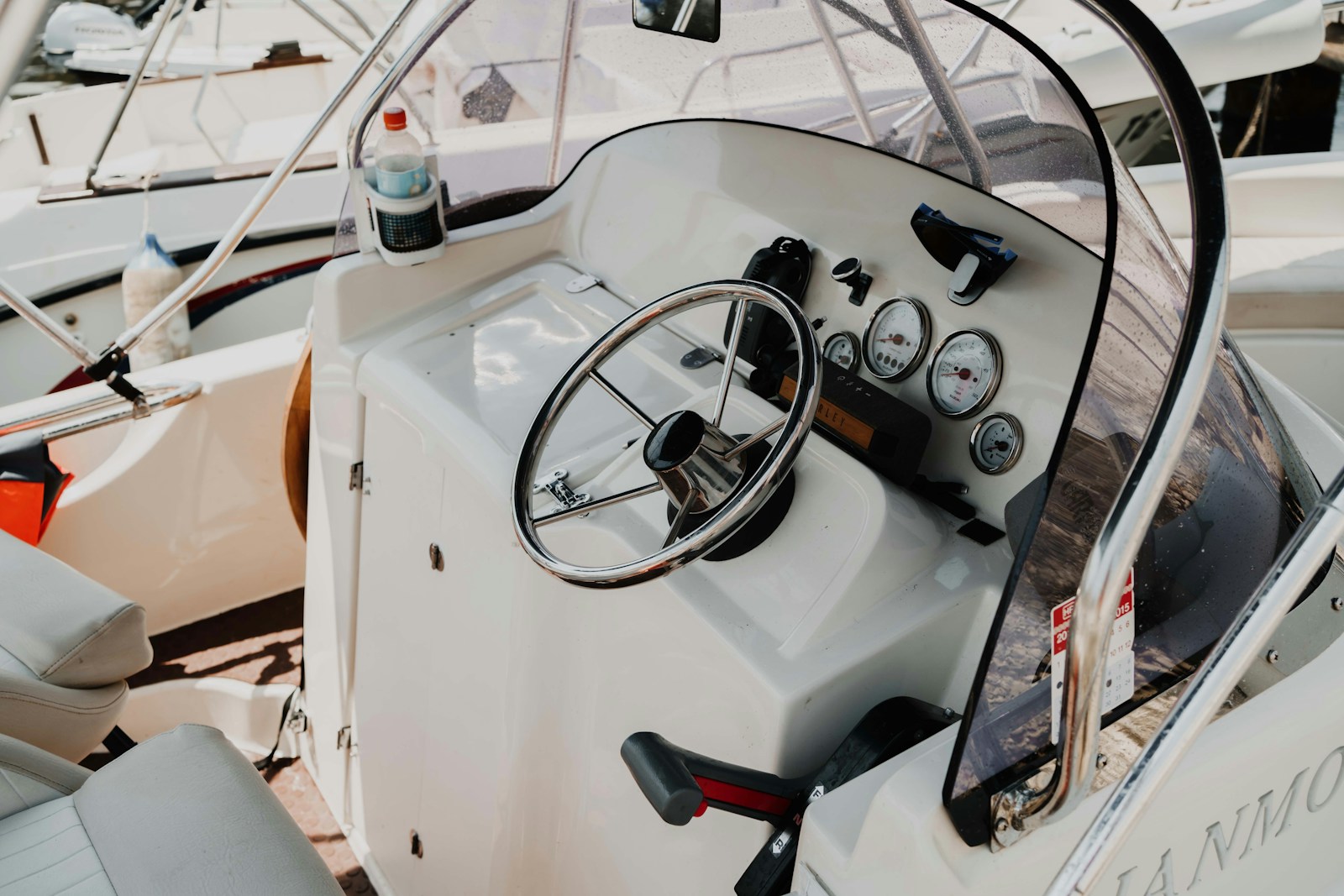 Stock photo of a white boat helm with stainless steering wheel, gauges, and upholstered seating